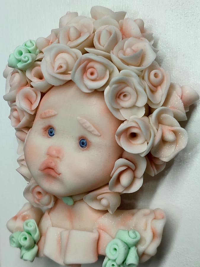 Cara de muñeca con flores en la cabeza modelada en porcelana fría por Evaninas.