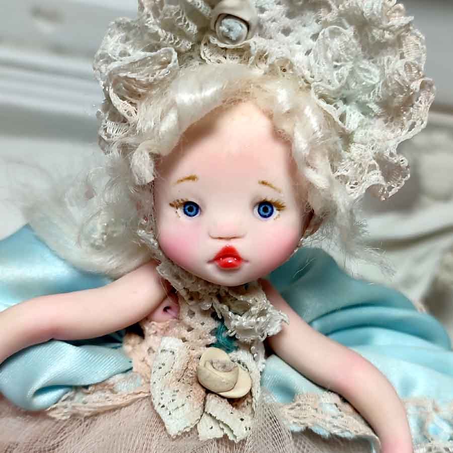 Muñeca con Libro Decorativo • Evaninas Cara de muñeca con rizos hecha a mano por Evaninas.